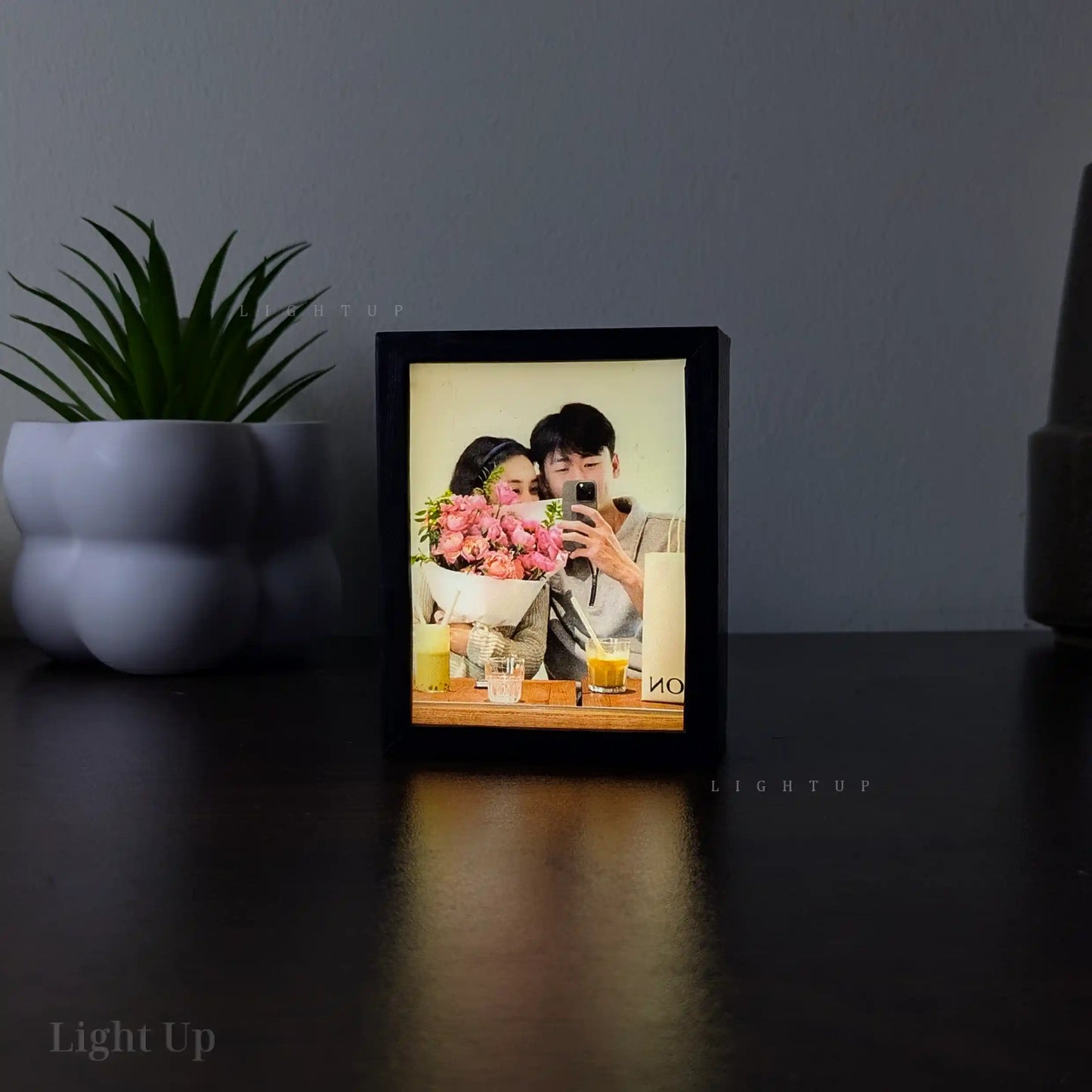 Display Mini, Framed lightbox with a photo of a couple with flowers on a dark surface, with 'Light Up' branding.